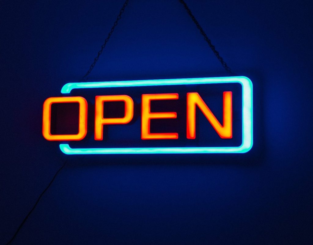 Brightly lit 'Open' neon sign against a dark background, creating a vibrant and inviting atmosphere.